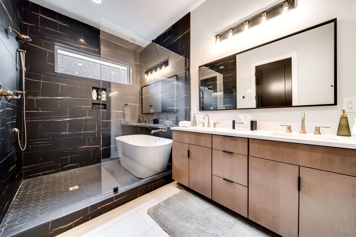 A luxurious, spa-inspired bathroom featuring a freestanding bathtub, glass shower enclosure, double-sink vanity with a large mirror, and abundant natural light. Clean lines and upscale fixtures evoke a high-end hotel spa ambiance.