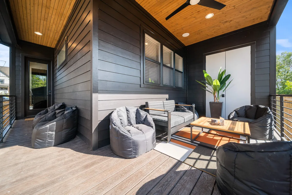 A comfortable outdoor seating area with bean bag chairs, a wooden table, and potted plants beside a sliding door, inviting residents to enjoy fresh air and socialize just outside the home.