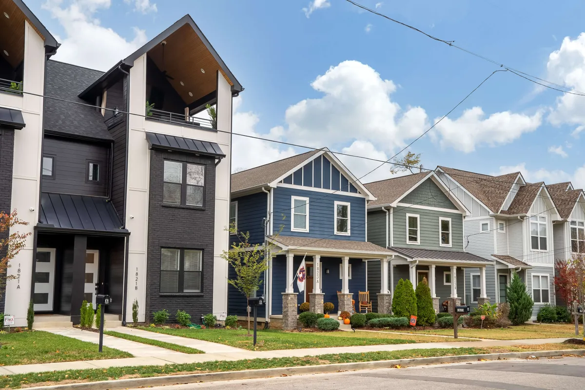 This image showcases the vibrant exterior of the Buchanan Arts District neighborhood, featuring modern architecture, colorful facades, and landscaped gardens. People can be seen strolling and socializing, embodying the lively community spirit.